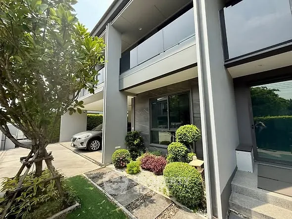 Modern two-story house with landscaped garden and carport in a serene neighborhood.