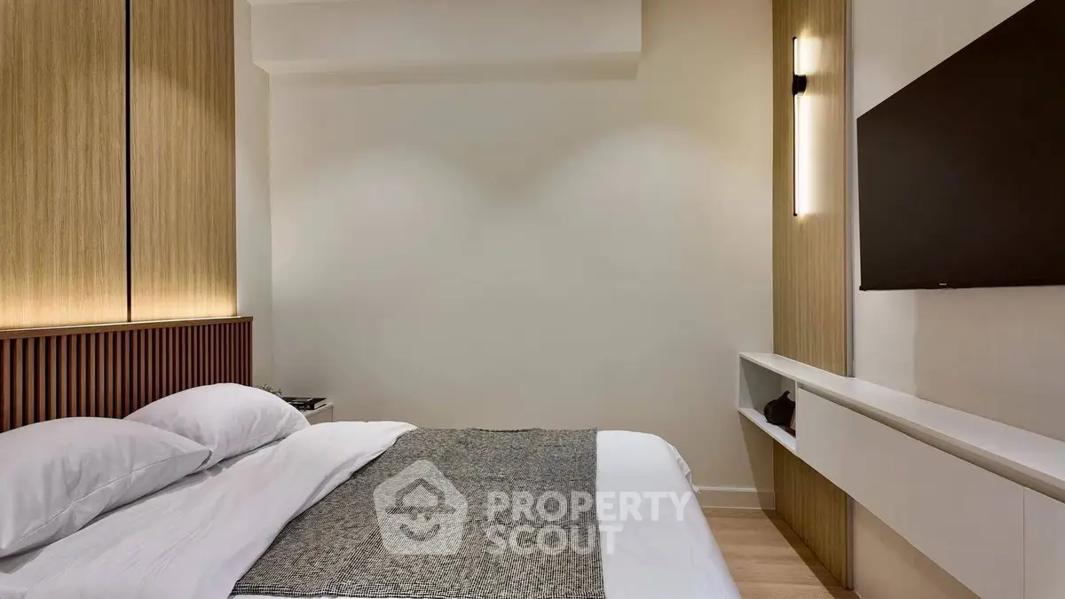 Modern bedroom with sleek design, featuring a wall-mounted TV and elegant lighting.