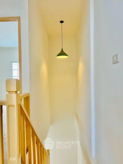 Bright staircase with modern pendant light and wooden railing