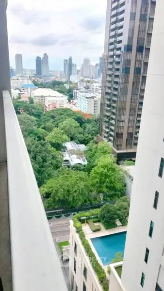 Stunning urban view from high-rise balcony overlooking cityscape and lush greenery.