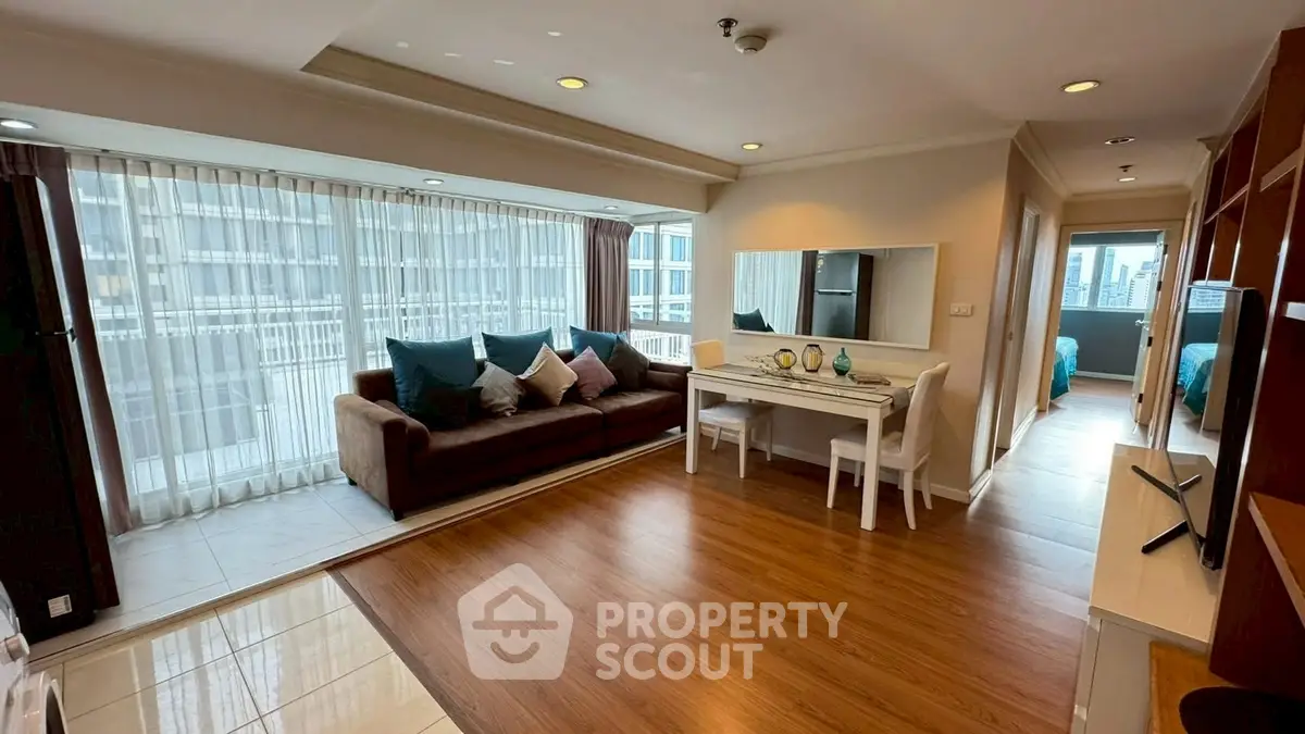 Spacious living room with large windows and modern decor in a high-rise apartment.