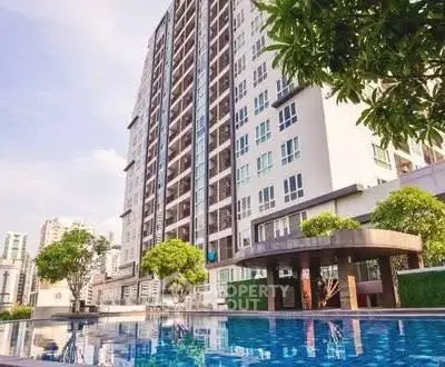 Modern high-rise building with a luxurious pool and lush greenery, perfect for urban living.