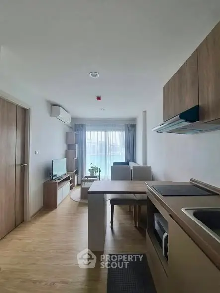 Modern open-layout living room with kitchen, featuring sleek wooden flooring and contemporary furniture.