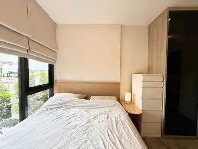 Cozy bedroom with large window and modern furnishings, offering a serene view and ample natural light.