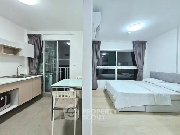 Modern studio apartment with open kitchen and cozy bedroom, featuring large windows and contemporary design.