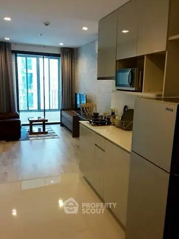 Modern open-layout living room with kitchen, featuring sleek appliances and large windows.