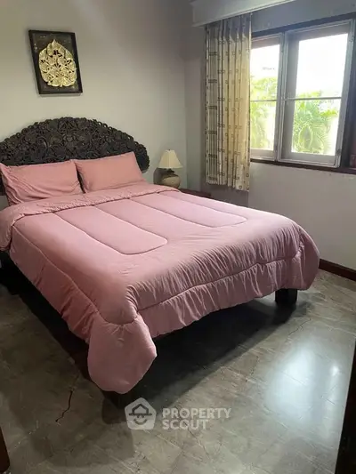 Cozy bedroom with elegant decor and natural light from large window.