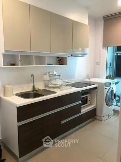 Modern kitchen with sleek cabinetry and built-in appliances, featuring a washing machine and ample counter space.