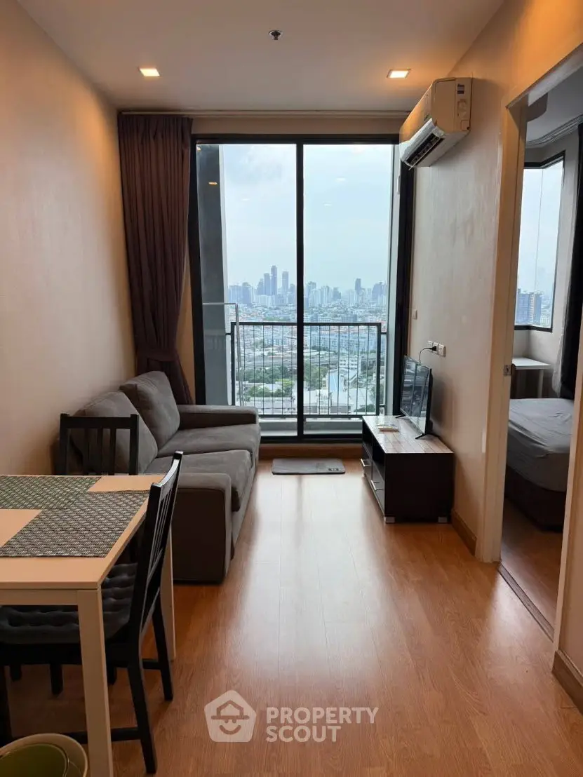 Modern living room with city view, featuring sleek furniture and large windows for natural light.