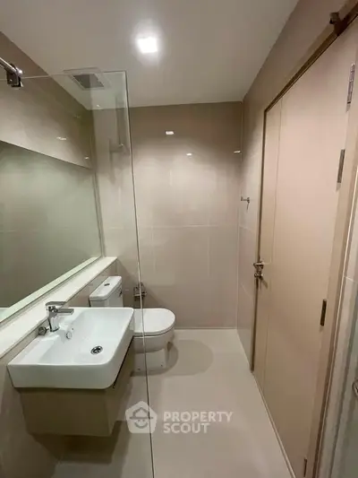 Modern bathroom with sleek fixtures and glass shower partition in a contemporary apartment.