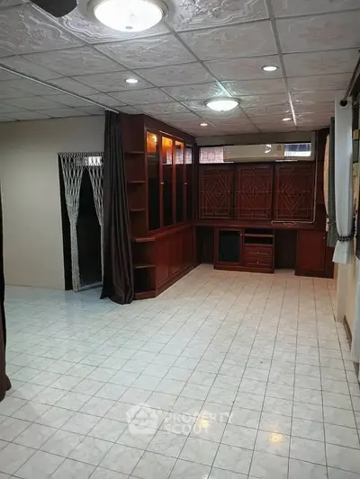 Spacious living room with built-in wooden shelves and tiled flooring, perfect for modern living.