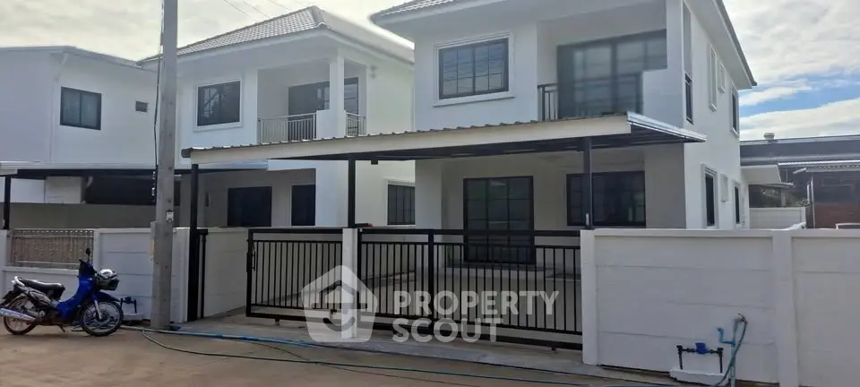 Modern two-story house with gated driveway and contemporary design in a suburban neighborhood.