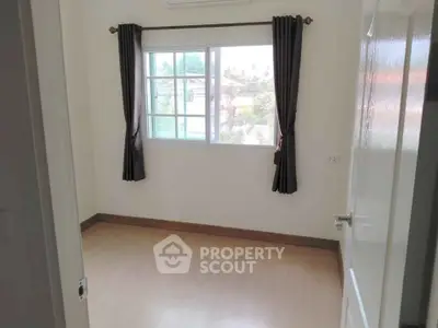 Bright empty room with large window and wooden flooring, perfect for customization.