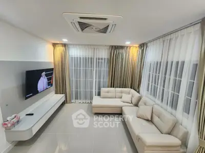 Modern living room with elegant sofa and large windows, perfect for relaxation and entertainment.
