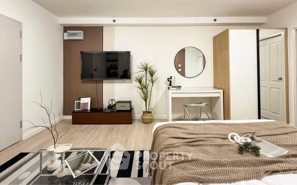 Modern bedroom with stylish decor, featuring a wall-mounted TV, cozy bed, and elegant furnishings.