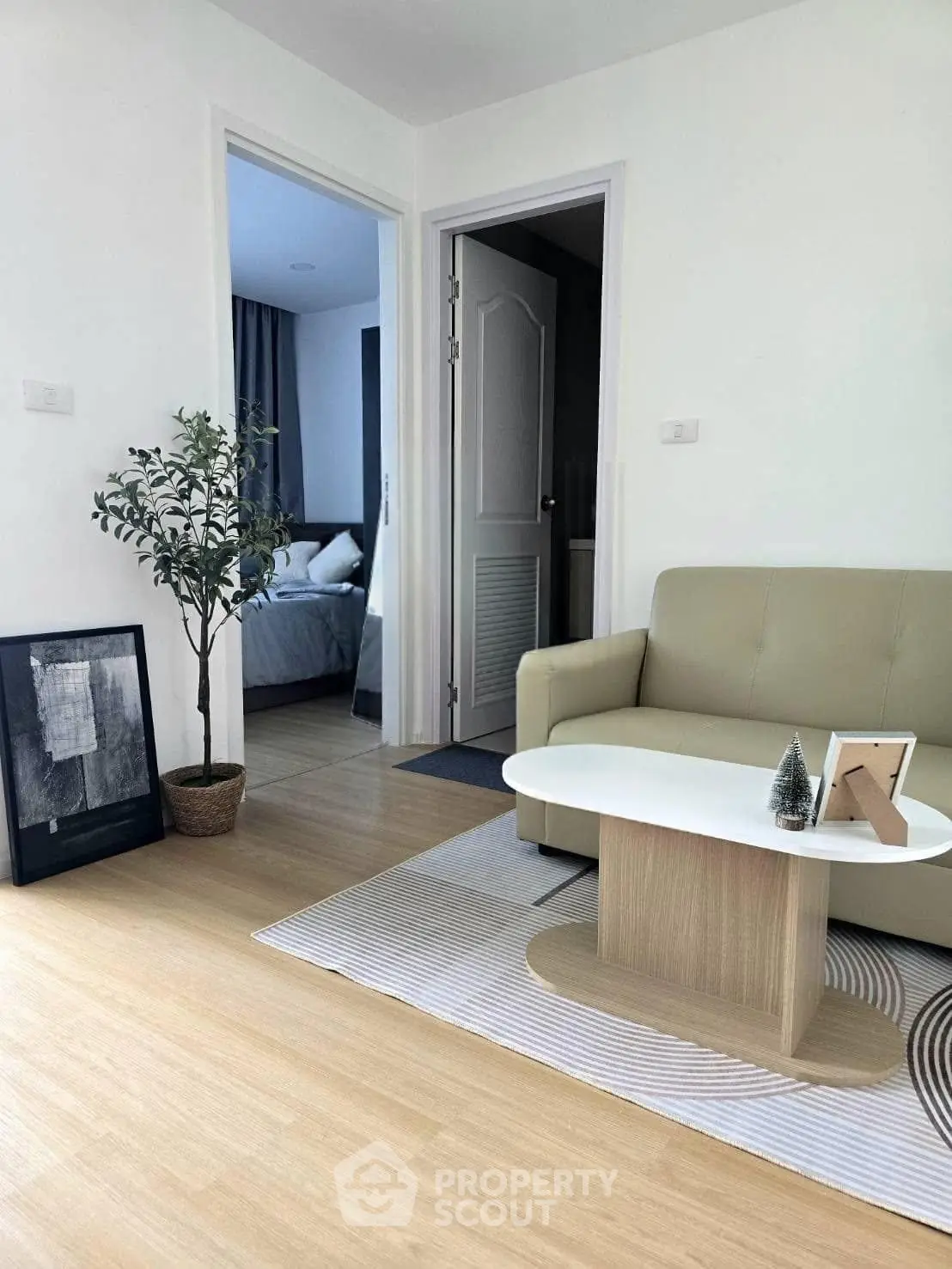Modern living room with cozy sofa and stylish decor leading to a bedroom, perfect for urban living.