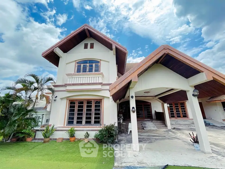 Charming two-story house with lush garden and spacious driveway under a bright blue sky.