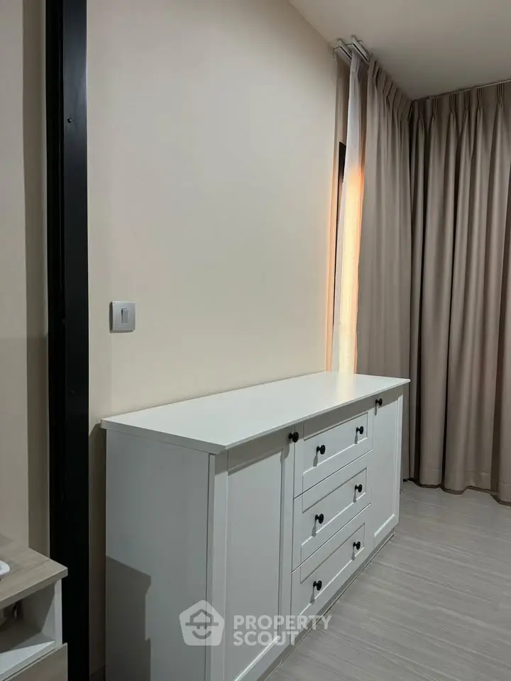 Modern interior with sleek white dresser and elegant curtains in a cozy room setting.