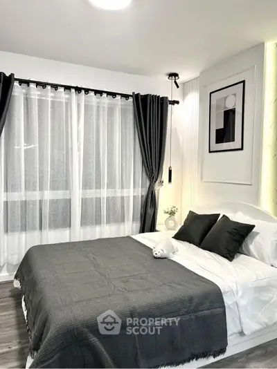 Modern bedroom with stylish decor and large window, featuring elegant curtains and cozy bedding.
