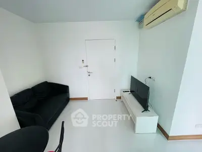 Compact living room with modern sofa and wall-mounted TV, featuring sleek white flooring.
