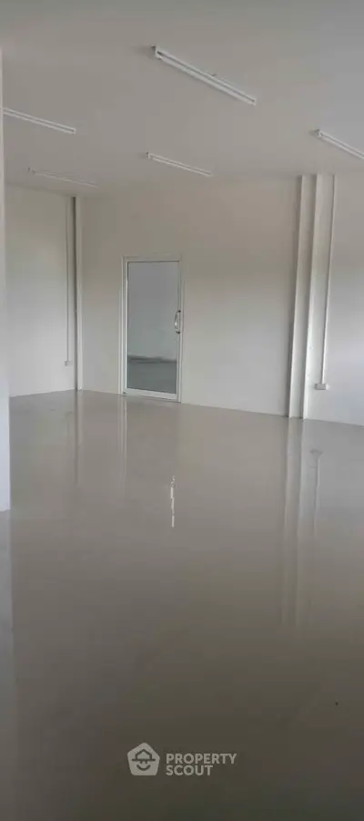 Spacious empty room with glossy tiled flooring and modern lighting, ideal for customization.