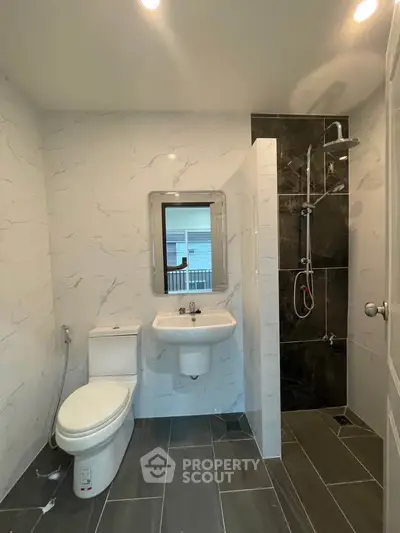 Modern bathroom with sleek design, featuring a shower, toilet, and sink with a large mirror.