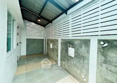 Modern covered patio with tiled flooring and privacy wall
