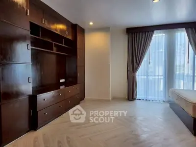 Spacious bedroom with elegant wooden built-in storage and large windows.