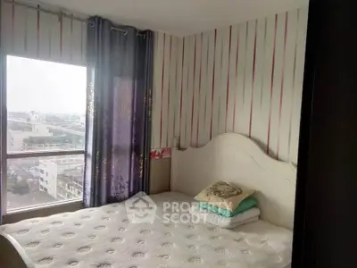Cozy bedroom with large window offering city view and elegant striped wallpaper.