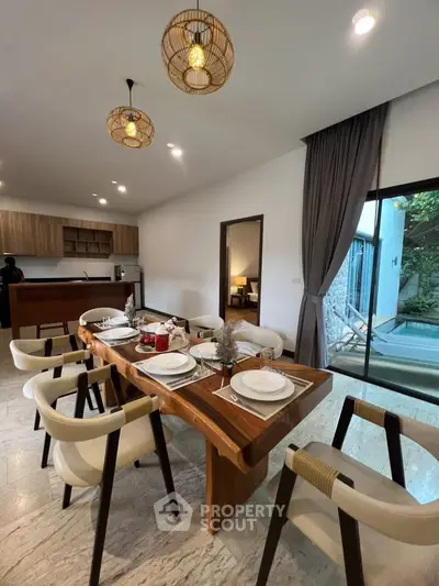 Luxurious dining area with elegant wooden table, modern chairs, and open kitchen in a stylish home.
