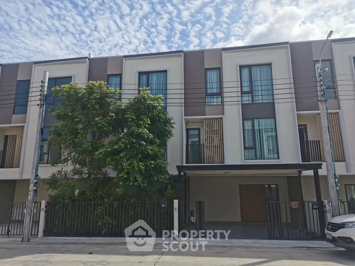 Modern townhouse exterior with sleek design and large windows under a blue sky.