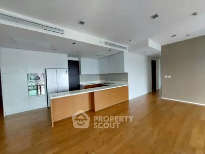 Spacious modern kitchen with wooden flooring and sleek cabinetry in open layout.