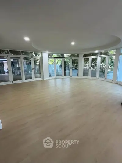 Spacious circular living room with large windows and wooden flooring