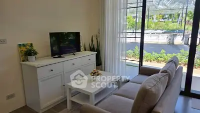 Cozy living room with modern decor and garden view, featuring a sleek TV stand and comfortable seating.