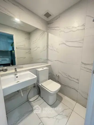 Modern bathroom with sleek white fixtures and marble-style tiles.