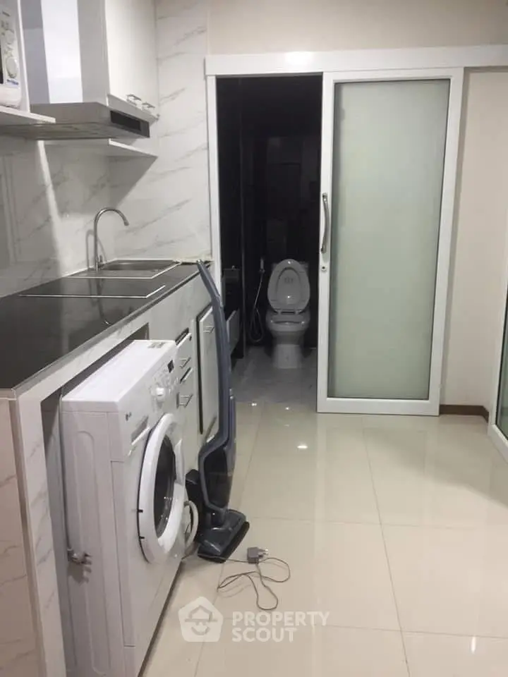 Compact kitchen with washing machine and sliding door leading to bathroom