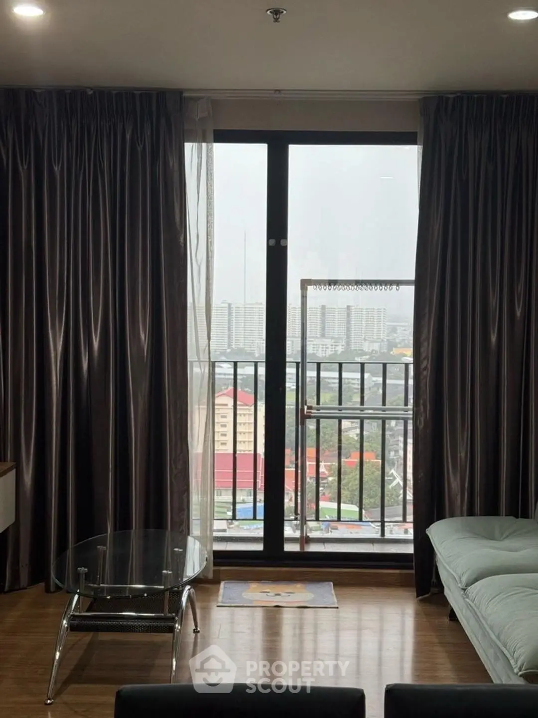 Modern living room with large window and city view, featuring stylish curtains and sleek furniture.