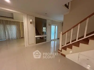 Spacious modern interior with elegant staircase and large windows for natural light.