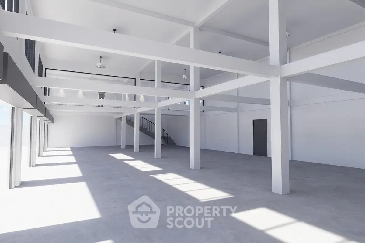 Spacious industrial-style open space with high ceilings and abundant natural light.