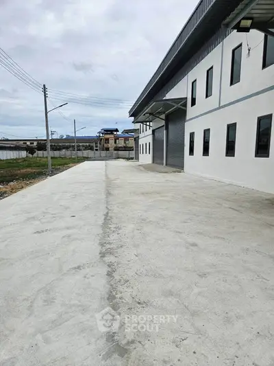 Spacious industrial warehouse exterior with large driveway and modern design.