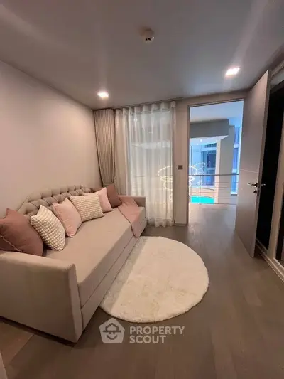 Cozy living room with elegant sofa and modern decor, featuring a view of the pool area.