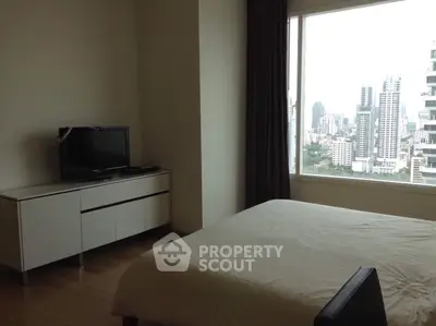 Modern bedroom with city view and sleek furniture in high-rise apartment.