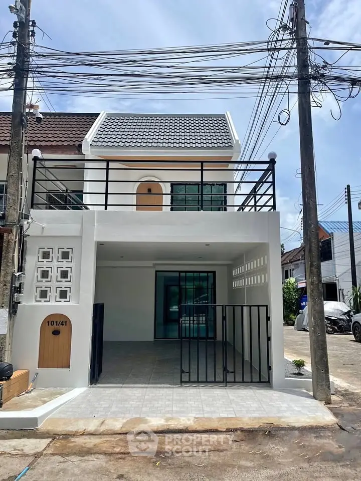 Modern two-story townhouse with gated entrance and tiled driveway in a suburban neighborhood.