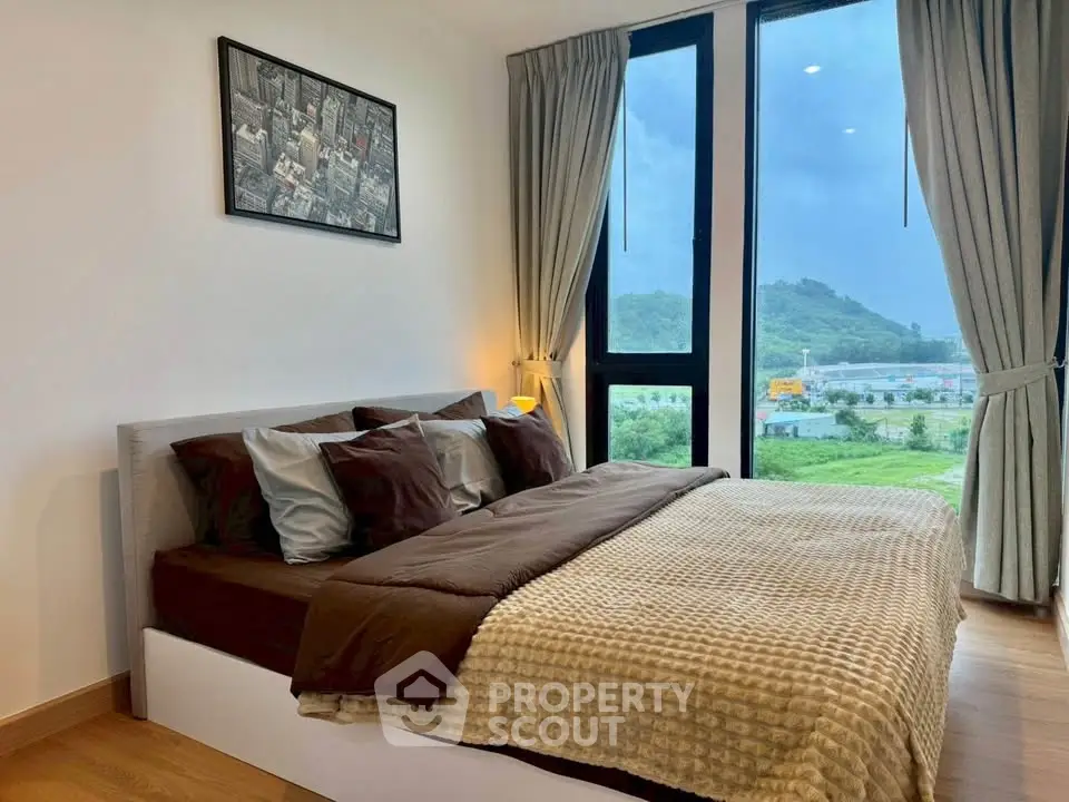 Modern bedroom with large windows offering scenic views of lush greenery and hills.