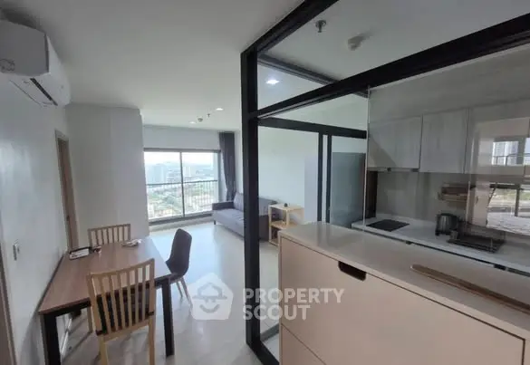 Modern open-plan living room with kitchen and city view, featuring sleek furniture and large windows.