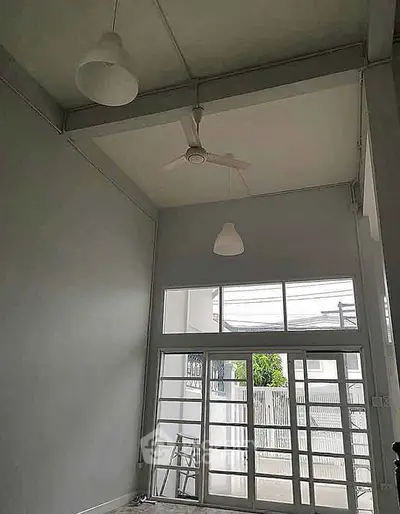 Spacious room with high ceiling and large windows offering ample natural light.