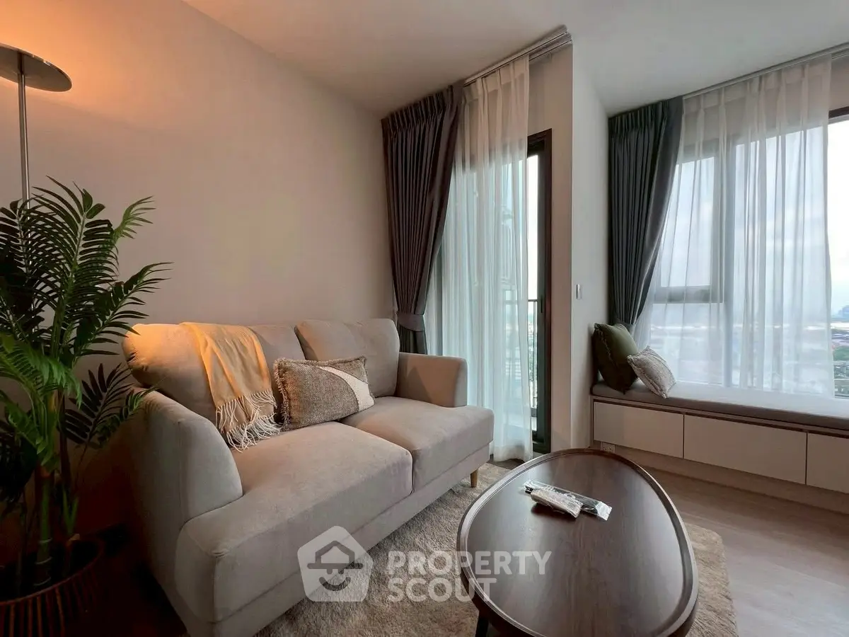 Cozy living room with modern decor and large windows offering a stunning city view.