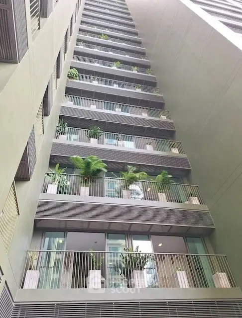 Modern apartment building with lush balcony gardens and sleek architectural design.