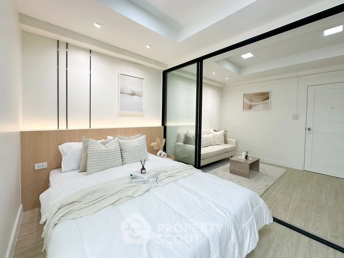 Modern bedroom with cozy bed and stylish decor adjacent to a chic living area.