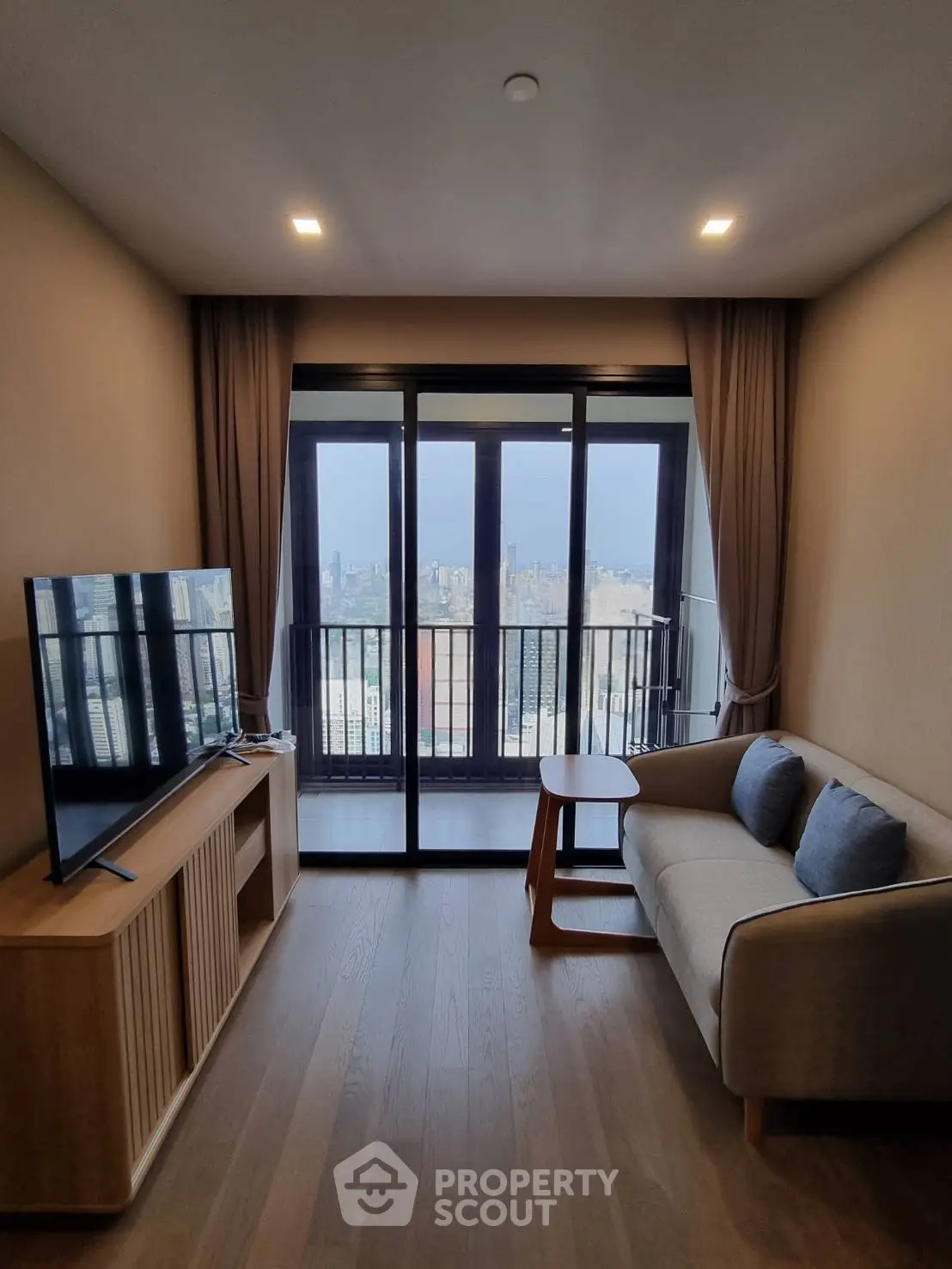 Modern living room with city view, featuring a sleek TV setup and cozy seating area.